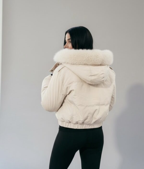 Страничен изглед на късо бежово яке с пухкава яка и модерен втален силует