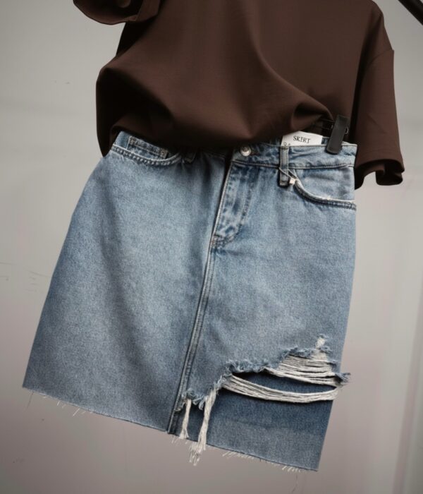 Страничен изглед на къса дънкова пола с разнищени краища и джобове Next Level