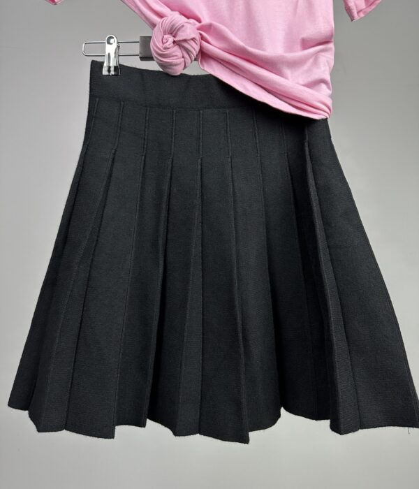 Детайл на подгъва и прецизните завършващи линии на плисирана пола в черно